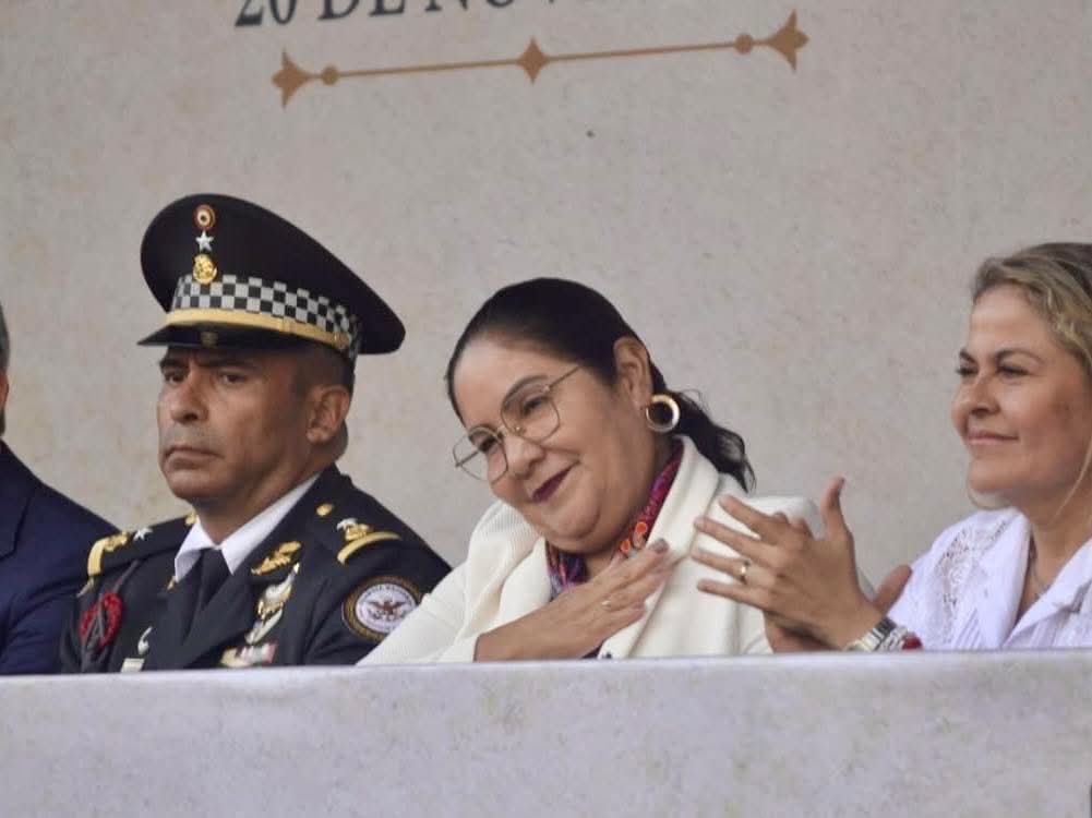 La secretaria de Educación de Veracruz, Dra. Claudia Tello Espinosa, recibiendo una ovación durante el desfile cívico del 20 de noviembre en Xalapa, rodeada de maestros, padres de familia y alumnos que reconocen su apoyo a las escuelas del estado.